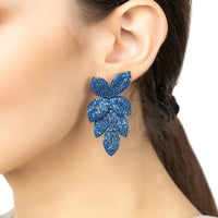 Blue rhinestone flower drop earrings on model's ear with gold-tone backing