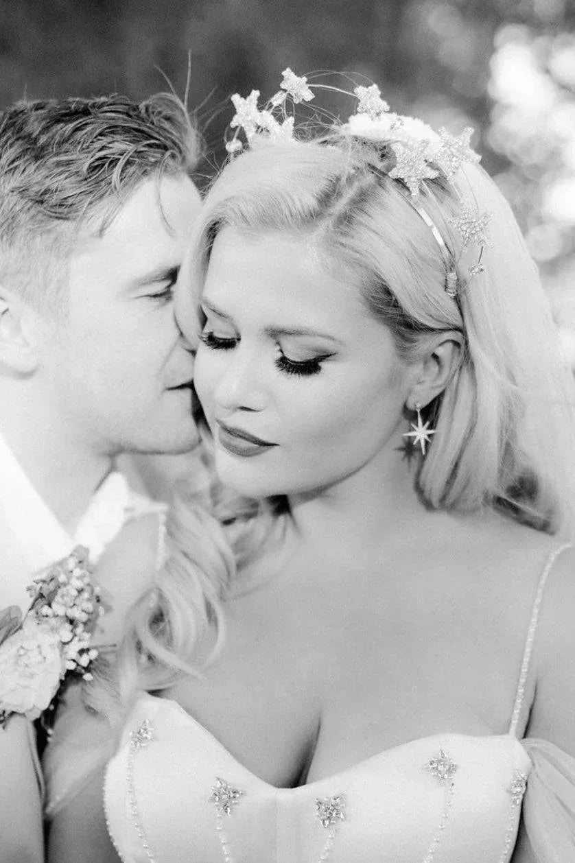Silver starburst drop earrings worn by a bride, featuring dangling star charms