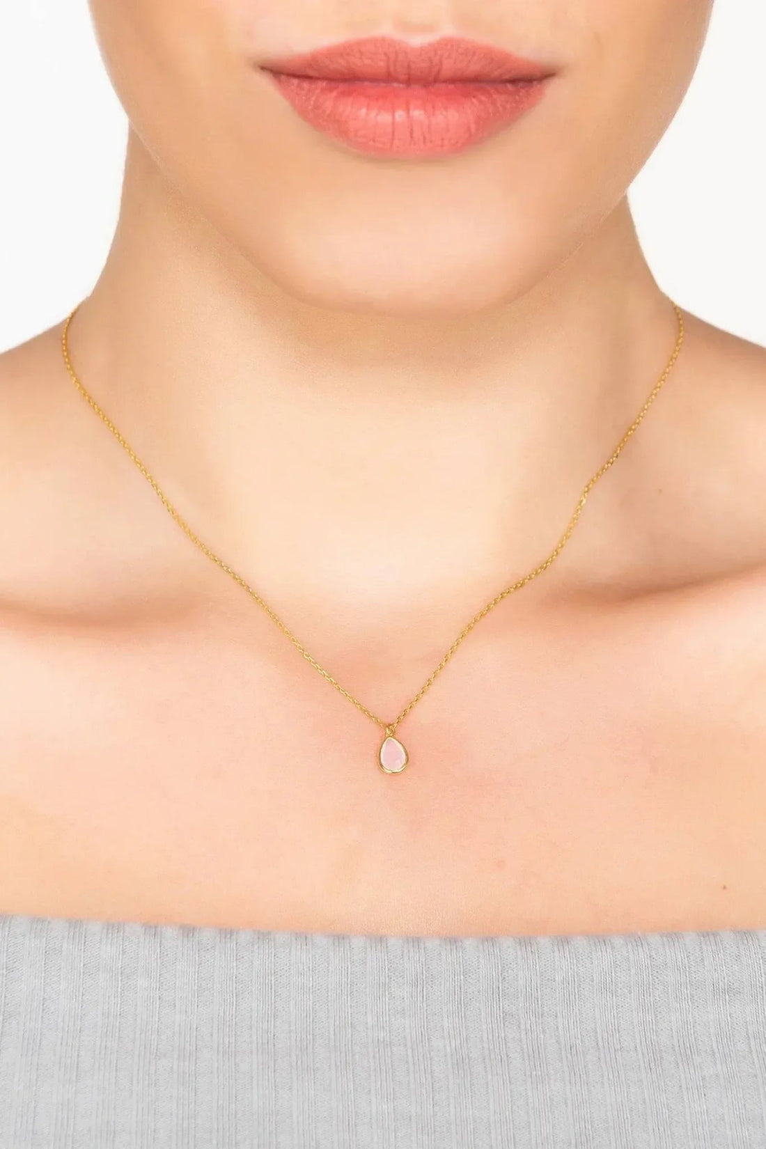 Gold mini teardrop pendant necklace worn at the collarbone