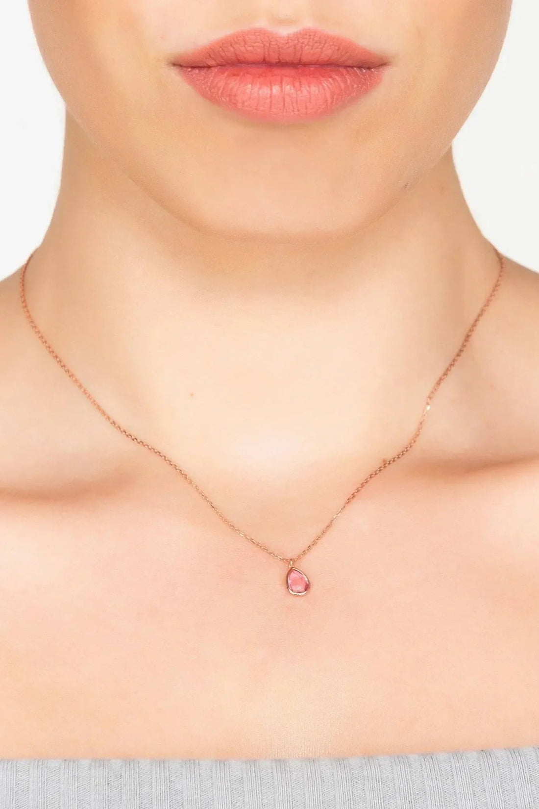 Rose gold teardrop pendant necklace with pink stone worn close to the neck