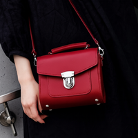 Red leather crossbody handbag with flap closure and silver clasp, adjustable strap