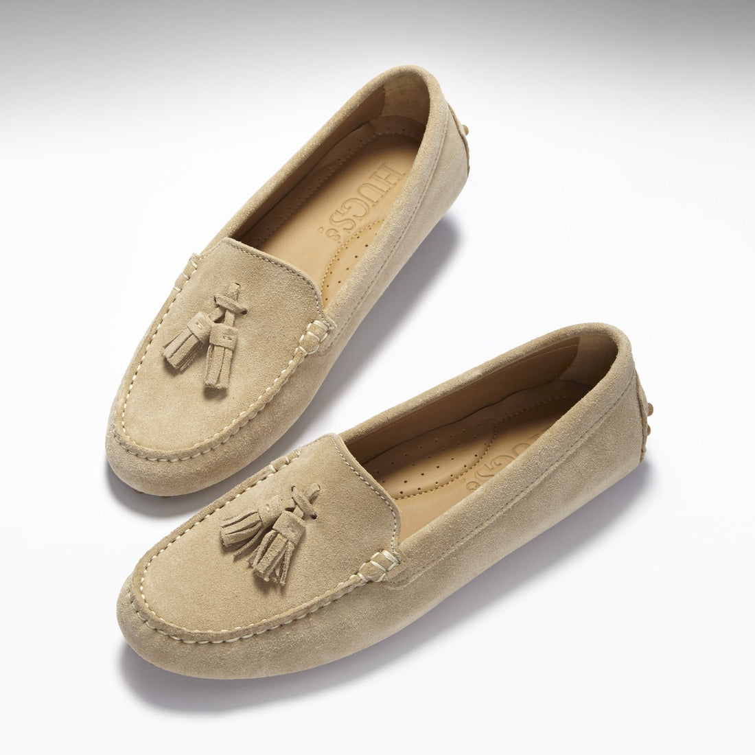 Pair of taupe suede loafers with moc toe stitching and tassels