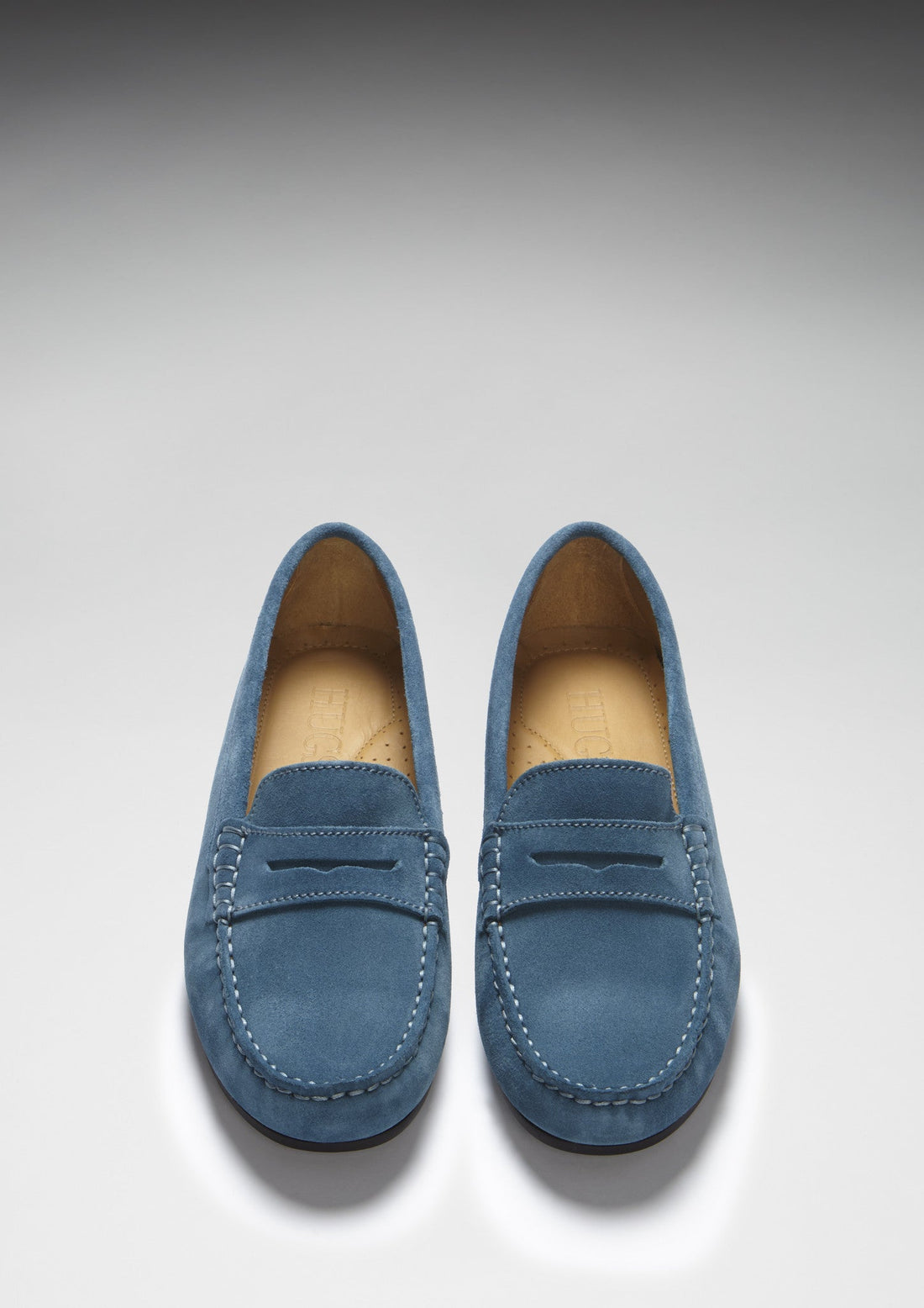 Pair of teal suede loafers shown from above, with penny straps and stitched toes