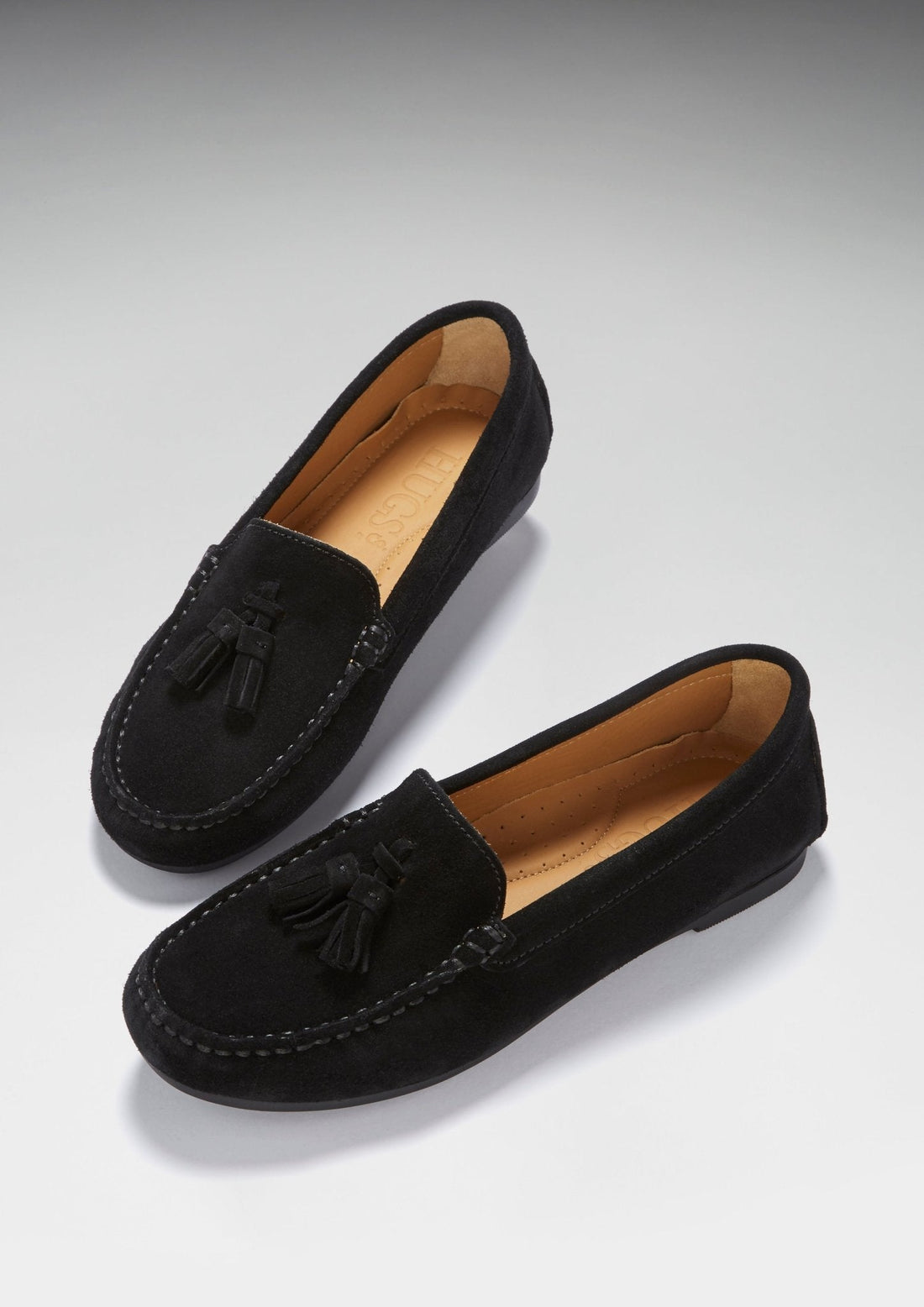 Pair of black suede loafers with tassel trim, shown at an angled top view
