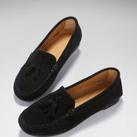 Pair of black suede loafers with tassel trim, shown at an angled top view