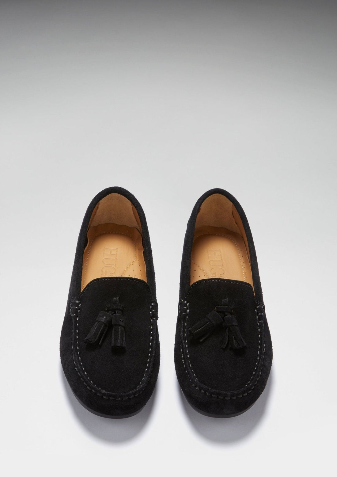 Pair of black suede tassel loafers viewed from above, showing tan insoles
