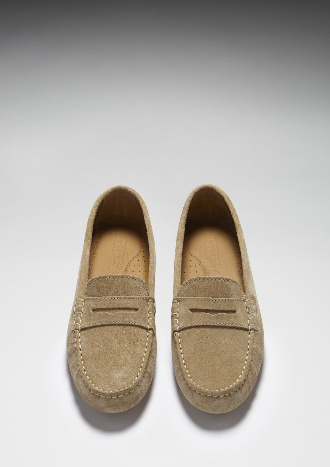 Pair of taupe suede loafers shown from above, with penny straps and moc stitching