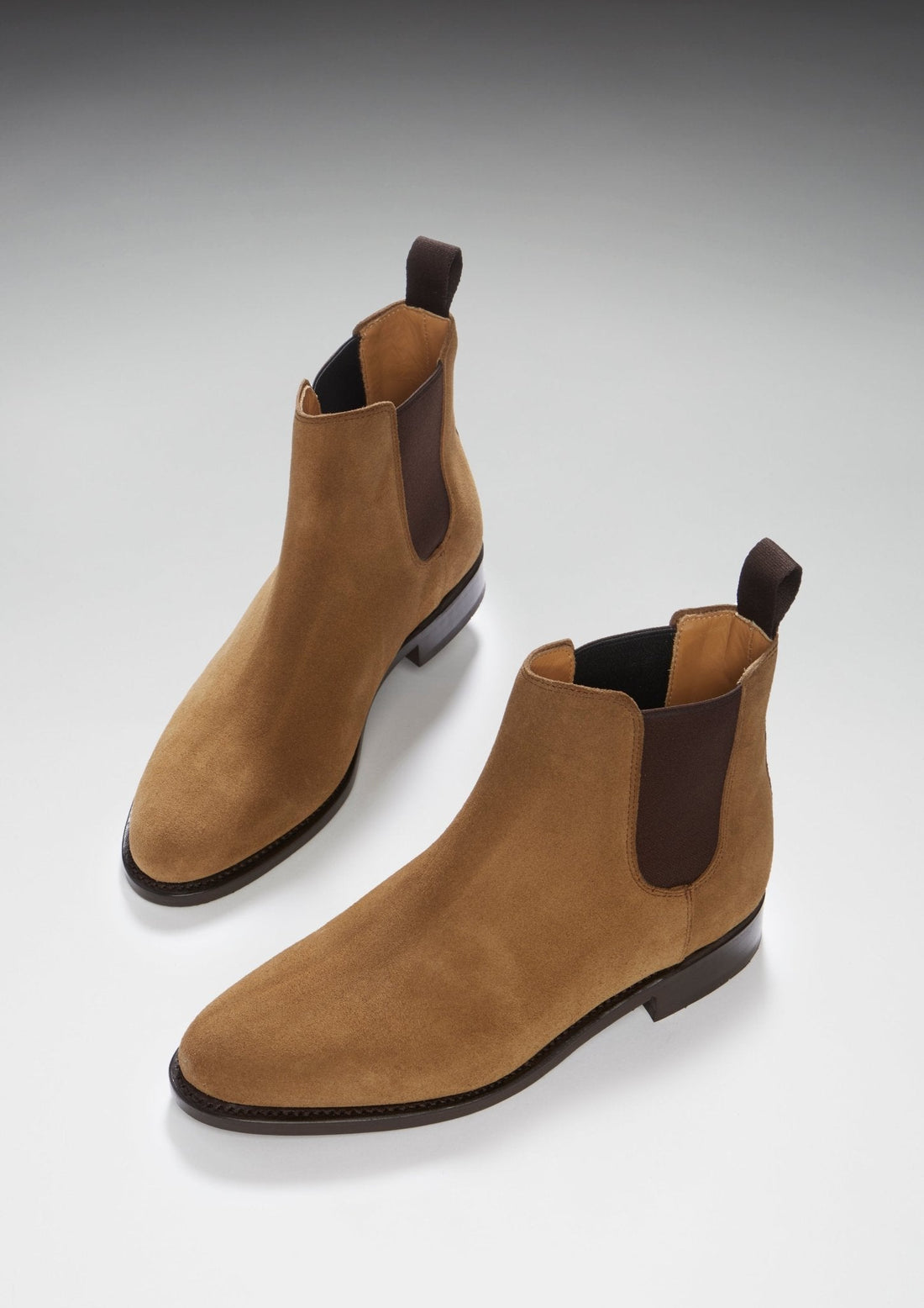 Pair of tan suede Chelsea boots shown at an angled view, with elastic side panels.