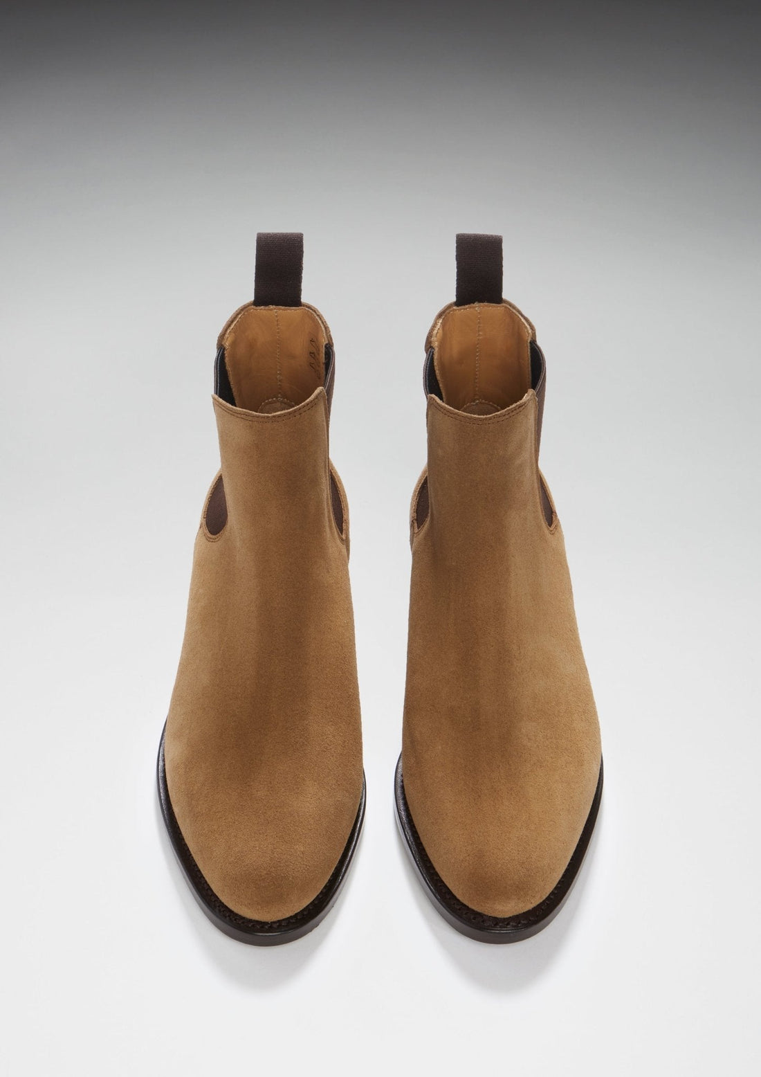 Pair of tan suede Chelsea boots with rounded toes and dark pull tabs.