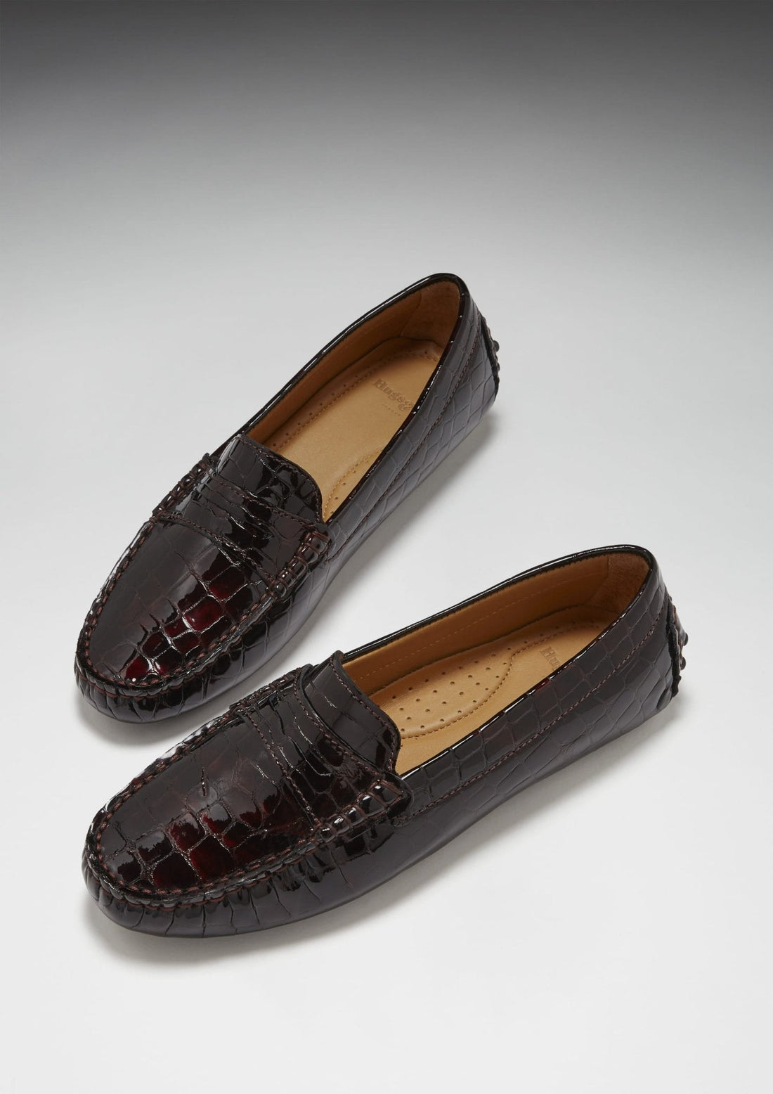 Pair of brown patent leather penny loafers with glossy croc-effect finish
