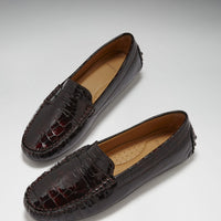 Pair of brown patent leather penny loafers with glossy croc-effect finish