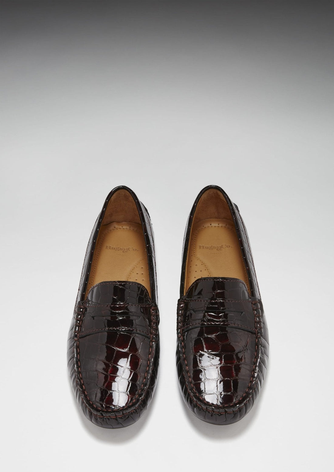 Pair of brown patent loafers viewed from above, showing penny straps and rounded toes