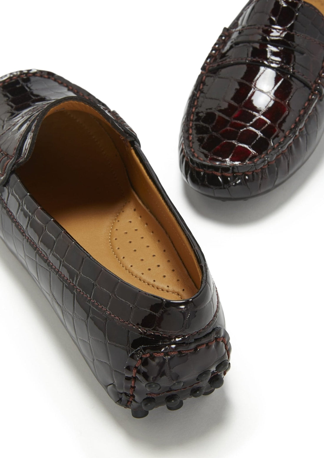 Patent leather loafer close-up showing croc-effect texture, stitched seams, and rubber heel nubs