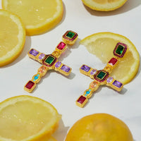Gold cross gemstone earrings with green, red, purple, and blue accents