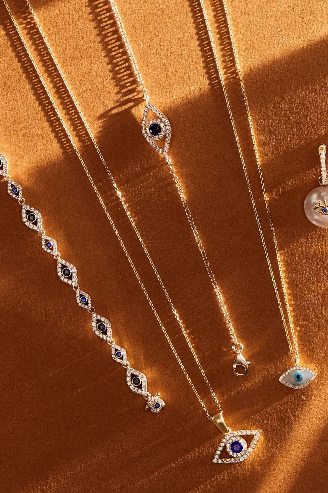 Gold-tone evil eye charm bracelets with blue oval stones and dangling eye pendants