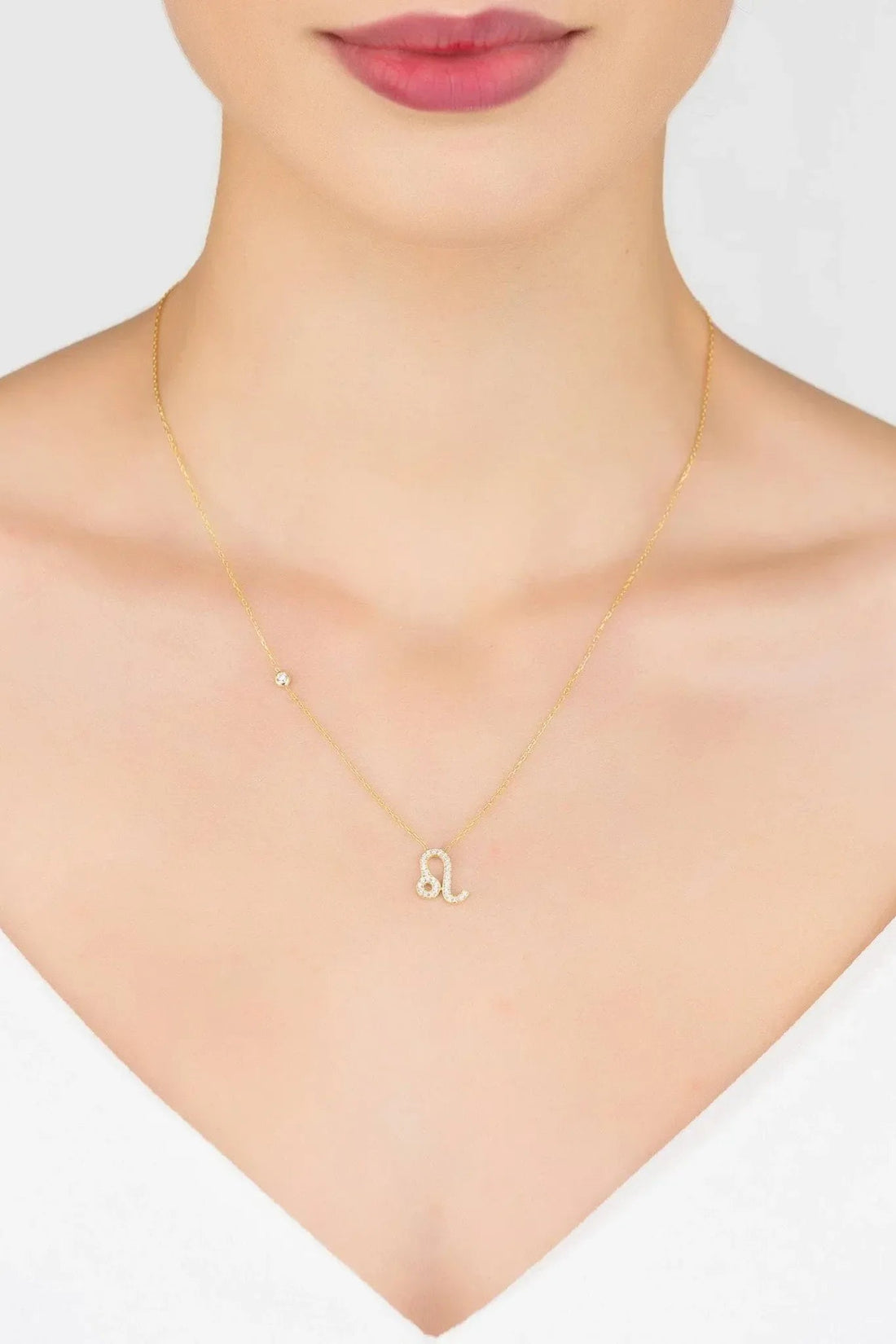 Gold zodiac pendant necklace on model with Leo symbol charm at the collar