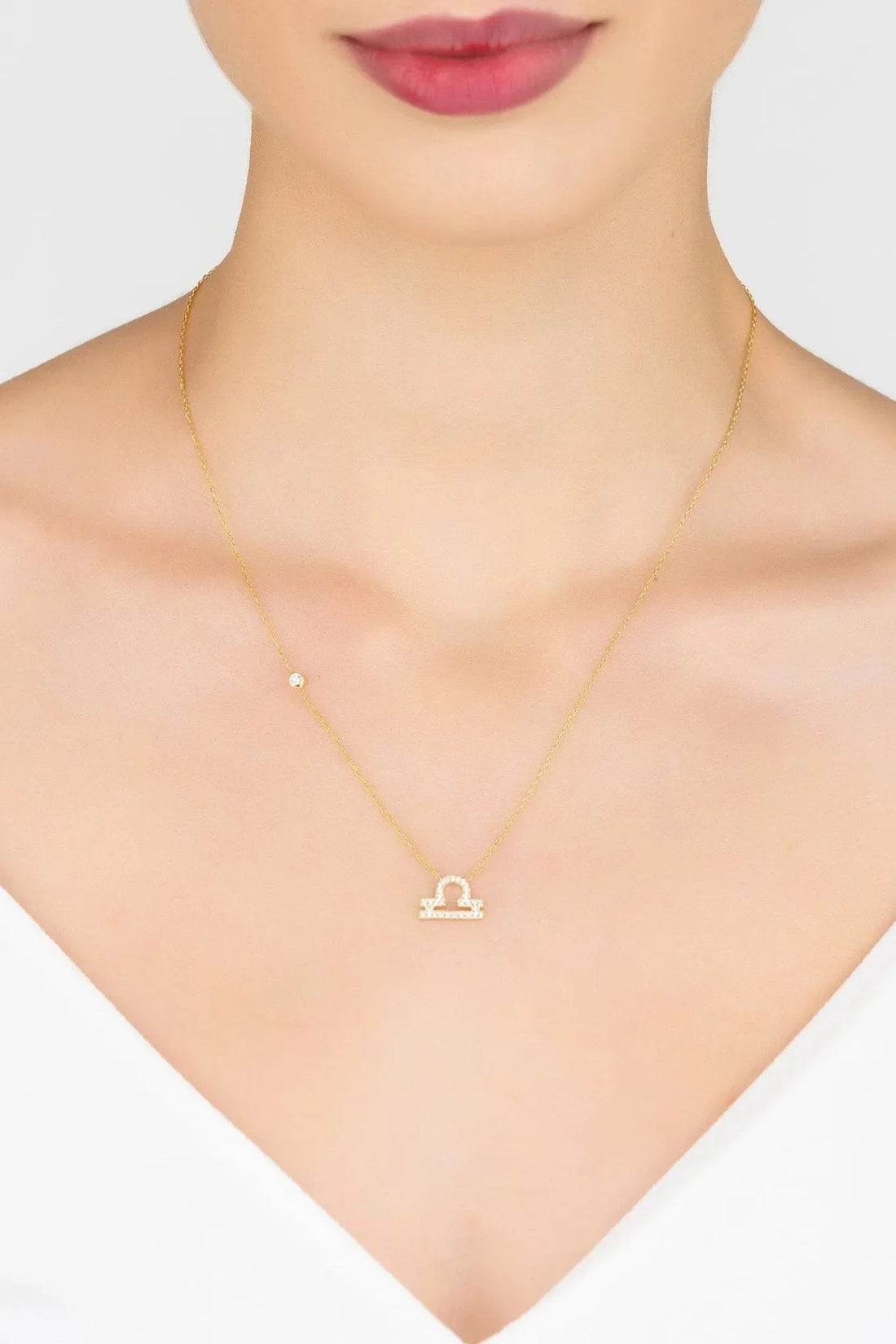 Gold Libra scale pendant necklace worn at the neckline