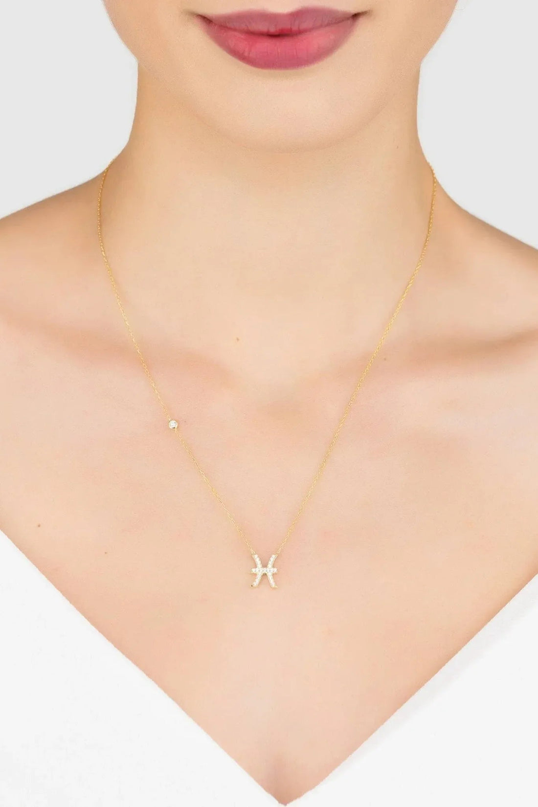 Gold Pisces zodiac pendant necklace on neckline, thin chain