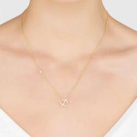 Gold Sagittarius pendant necklace with stylized symbol charm worn on neckline