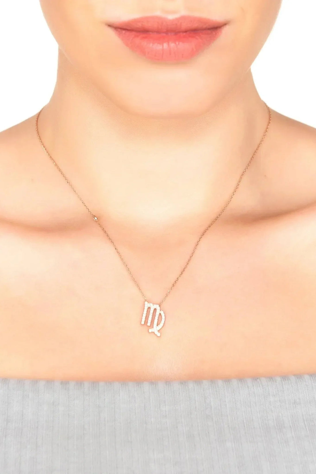 Rose gold Virgo zodiac pendant necklace on neckline with thin chain and small bead links.
